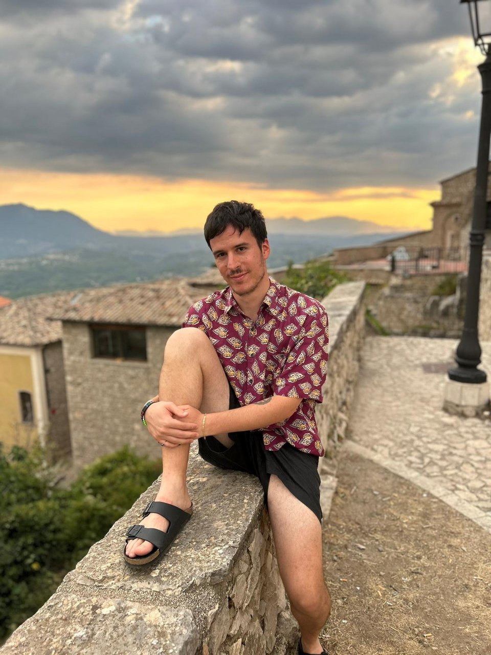 Foto di Carlo Polato, ha una camicia decorata a fantasia, guarda in camera e sorride, ha i capelli scuri 